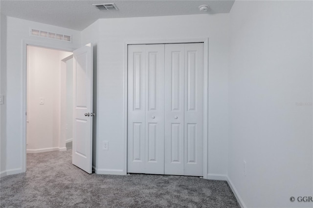 unfurnished bedroom featuring a textured ceiling, light carpet, and a closet