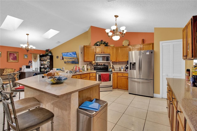 kitchen with hanging light fixtures, lofted ceiling with skylight, and stainless steel appliances