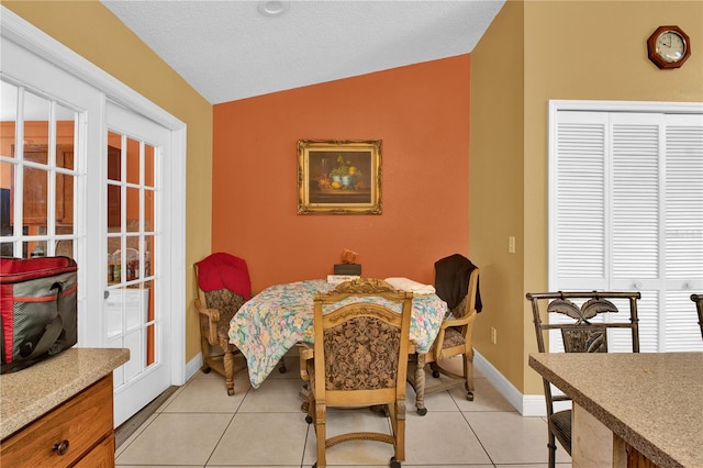 dining space featuring a textured ceiling, lofted ceiling, and light tile patterned flooring