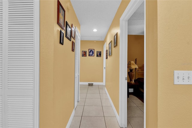 hall featuring a textured ceiling and light tile patterned floors