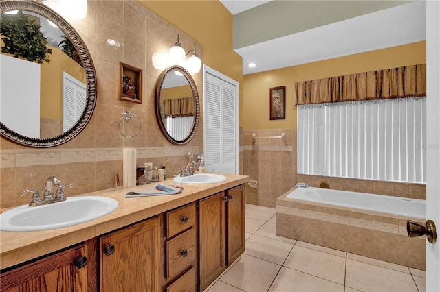 bathroom featuring tile walls, tiled tub, vanity, and tile patterned flooring