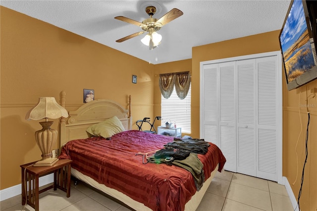 tiled bedroom with ceiling fan, a textured ceiling, and a closet