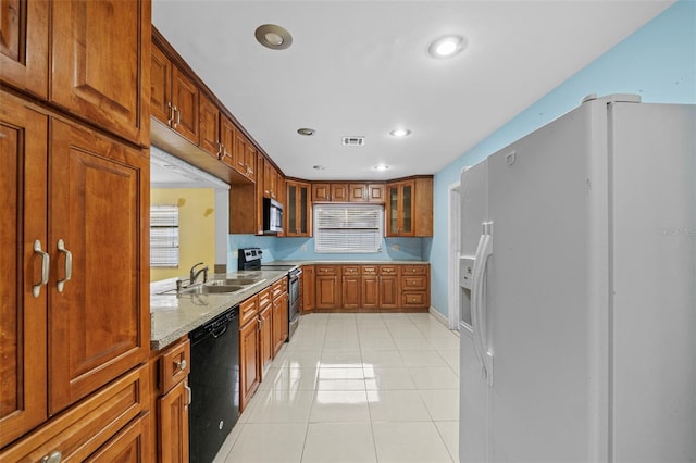 kitchen featuring light stone counters, appliances with stainless steel finishes, light tile patterned flooring, and sink