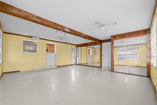 unfurnished room featuring wood walls and beamed ceiling