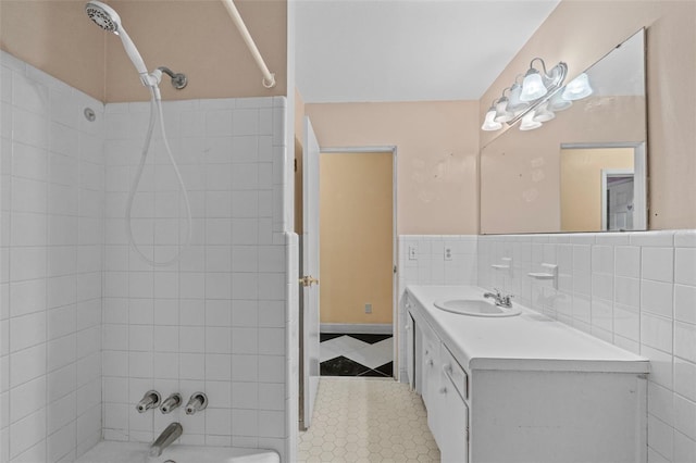 bathroom with tile walls, tiled shower / bath combo, and vanity