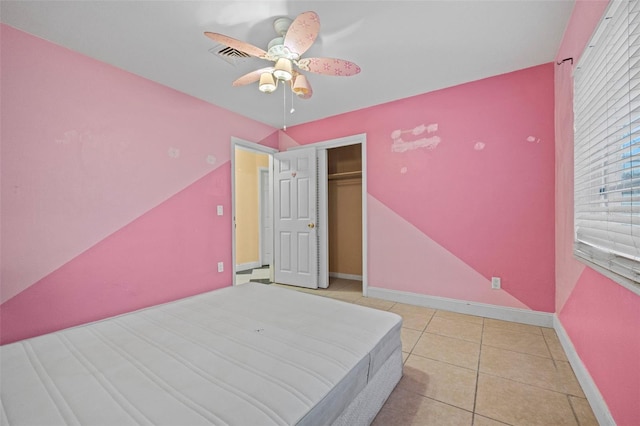 unfurnished bedroom with light tile patterned floors, ceiling fan, and a closet