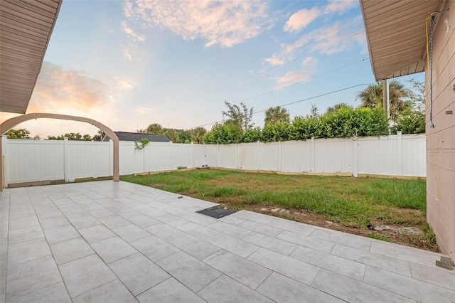 patio terrace at dusk featuring a lawn