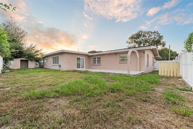 912 Ave T SE, Winter Haven, FL 33880 - back of property at dusk with a storage shed, a yard, an outdoor structure, a patio area, and fence