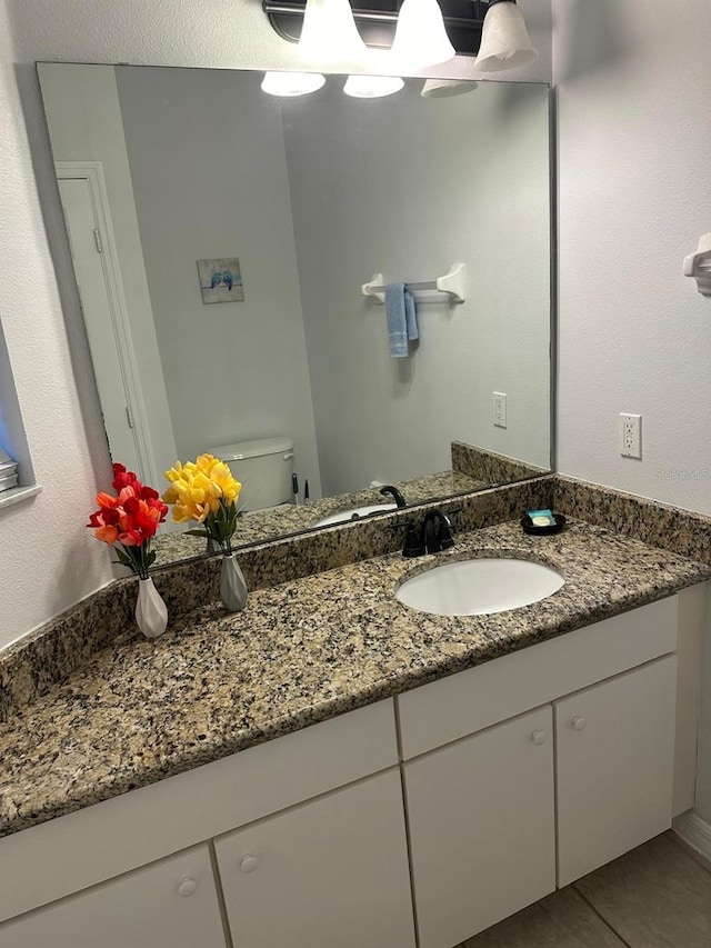 bathroom with tile patterned flooring, vanity, and toilet