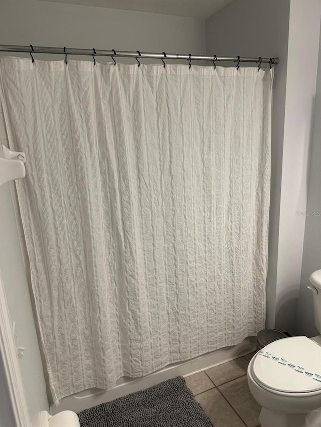 bathroom with a shower with shower curtain, toilet, and tile patterned floors