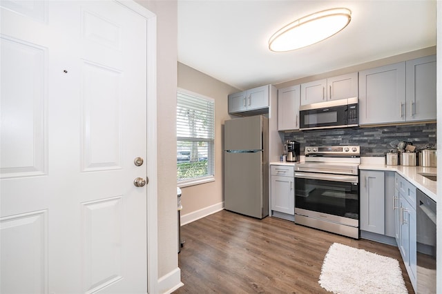 kitchen with gray cabinets, backsplash, appliances with stainless steel finishes, and dark hardwood / wood-style floors