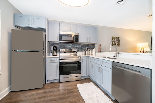 kitchen featuring tasteful backsplash, sink, kitchen peninsula, appliances with stainless steel finishes, and dark hardwood / wood-style flooring