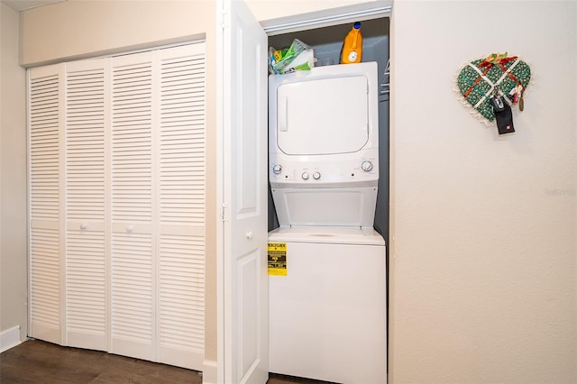 laundry area with dark hardwood / wood-style flooring and stacked washing maching and dryer