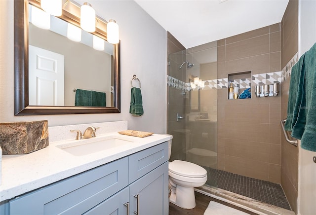 bathroom featuring wood-type flooring, vanity, toilet, and tiled shower