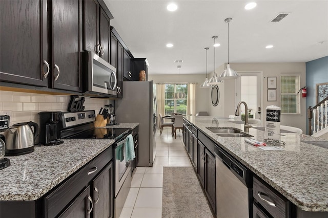 kitchen with pendant lighting, an island with sink, stainless steel appliances, and sink