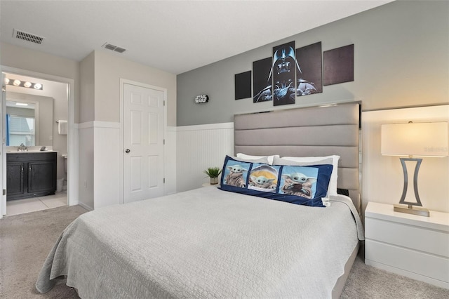 bedroom featuring light carpet and ensuite bath