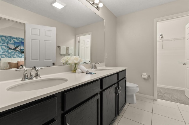 bathroom with tile patterned flooring, a textured ceiling, vanity, and toilet