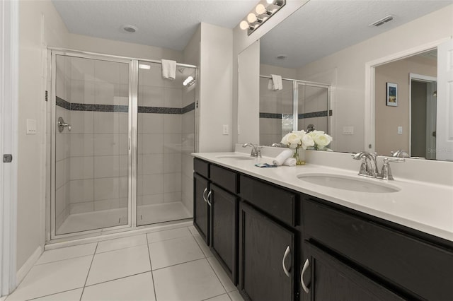 bathroom featuring a textured ceiling, vanity, tile patterned floors, and an enclosed shower