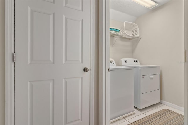 laundry area with a textured ceiling, washing machine and dryer, and light tile patterned floors