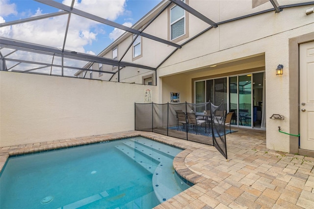 view of pool with glass enclosure and a patio area