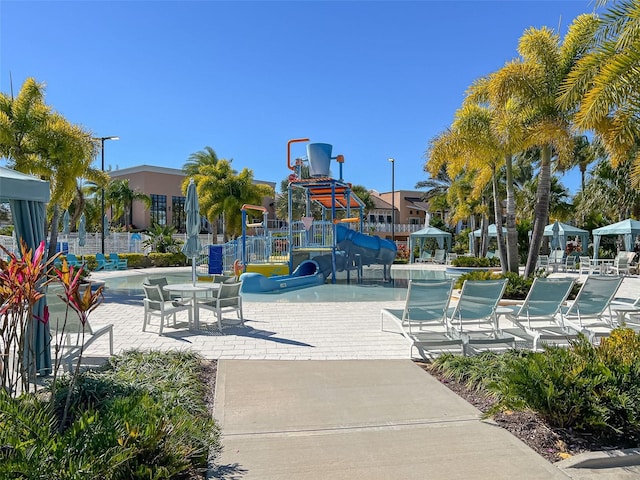 surrounding community featuring a playground, a pool, and a patio area