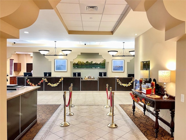 interior space featuring light tile patterned floors, a raised ceiling, and decorative light fixtures