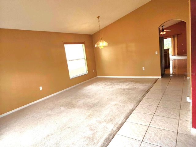 spare room featuring carpet flooring, a notable chandelier, vaulted ceiling, and a healthy amount of sunlight