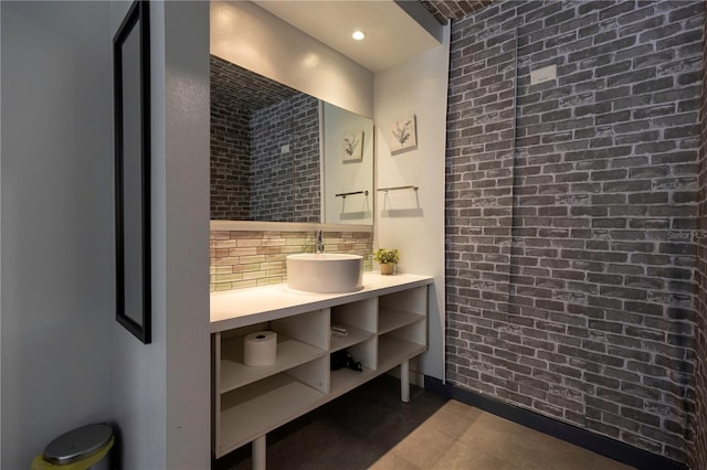 bathroom with recessed lighting, backsplash, brick wall, and a sink