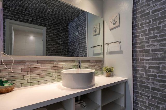 bathroom with vanity, tasteful backsplash, and brick wall