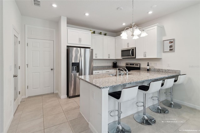 kitchen with appliances with stainless steel finishes, white cabinetry, light stone counters, kitchen peninsula, and pendant lighting