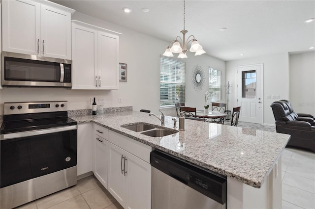 kitchen with appliances with stainless steel finishes, kitchen peninsula, sink, and white cabinets