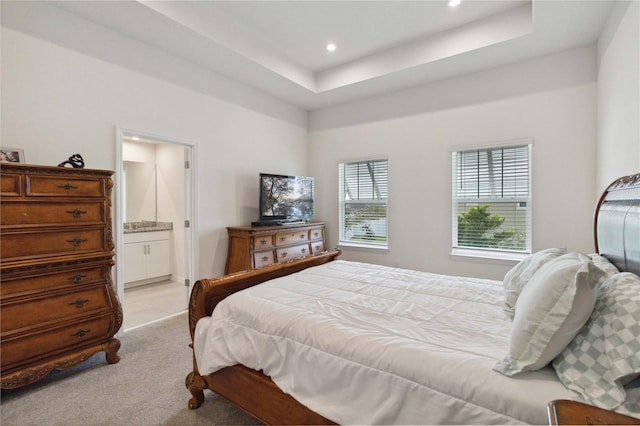 carpeted bedroom with a tray ceiling and connected bathroom