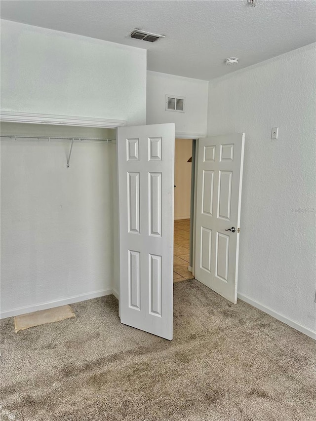 unfurnished bedroom with carpet floors, a textured ceiling, and a closet