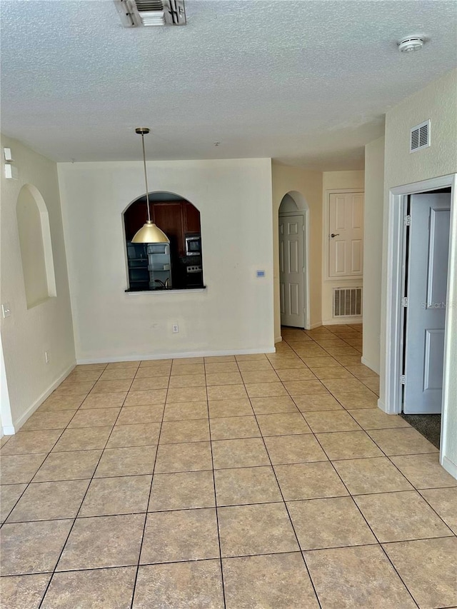 tiled empty room featuring a textured ceiling