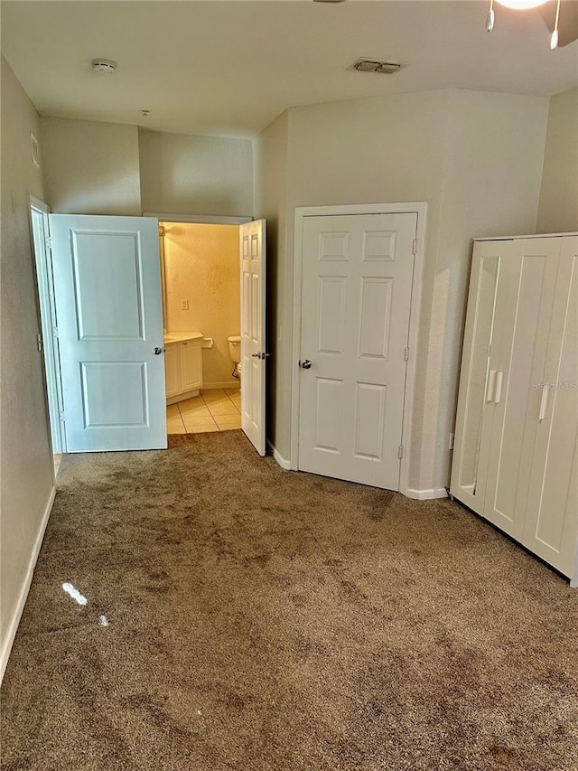 unfurnished bedroom featuring ensuite bathroom and light colored carpet