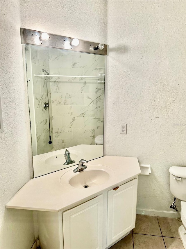 bathroom featuring toilet, tile patterned flooring, vanity, and tiled shower