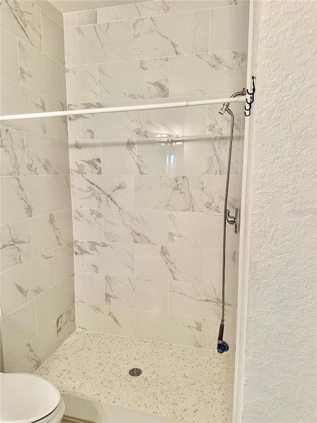 bathroom with a tile shower and toilet