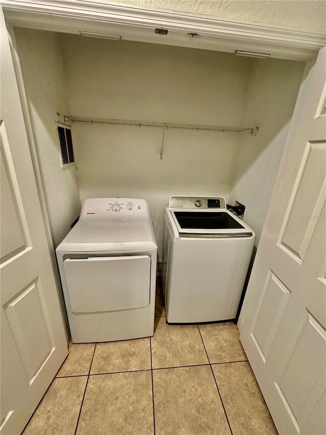 washroom with washer and dryer and light tile patterned floors