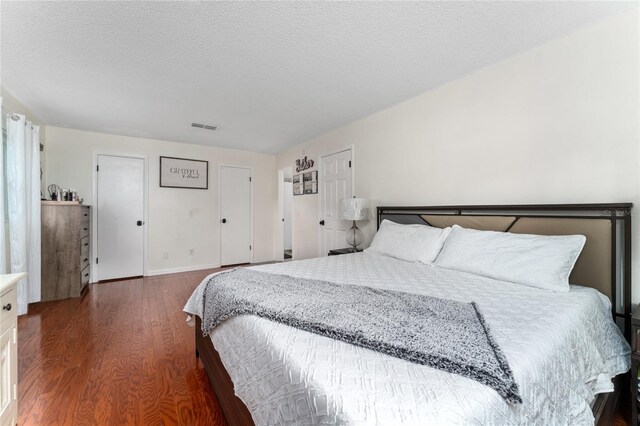 bedroom with a textured ceiling and dark wood-type flooring