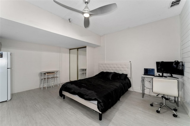 bedroom featuring ceiling fan, light hardwood / wood-style floors, and white fridge