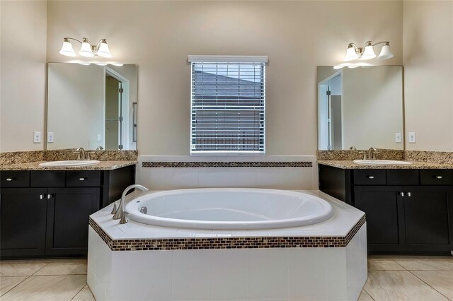 bathroom with tiled tub, tile patterned flooring, and vanity