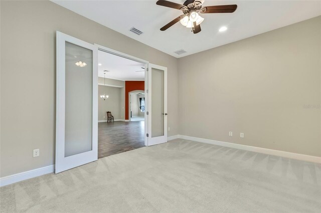 carpeted empty room featuring french doors and ceiling fan with notable chandelier