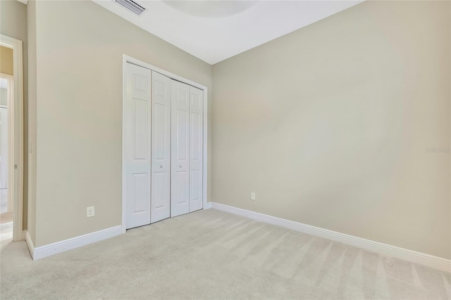 unfurnished bedroom featuring light colored carpet and a closet