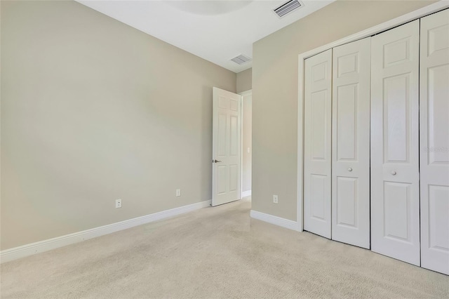 unfurnished bedroom with light colored carpet and a closet