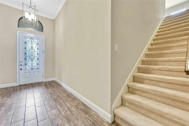 foyer entrance featuring crown molding, hardwood / wood-style floors, and a notable chandelier