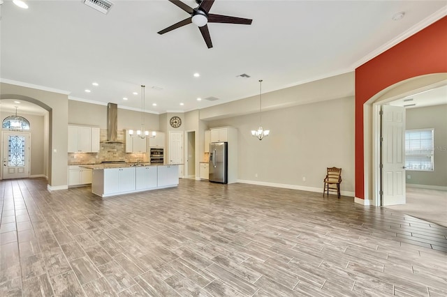 kitchen featuring white cabinets, appliances with stainless steel finishes, pendant lighting, and wall chimney exhaust hood