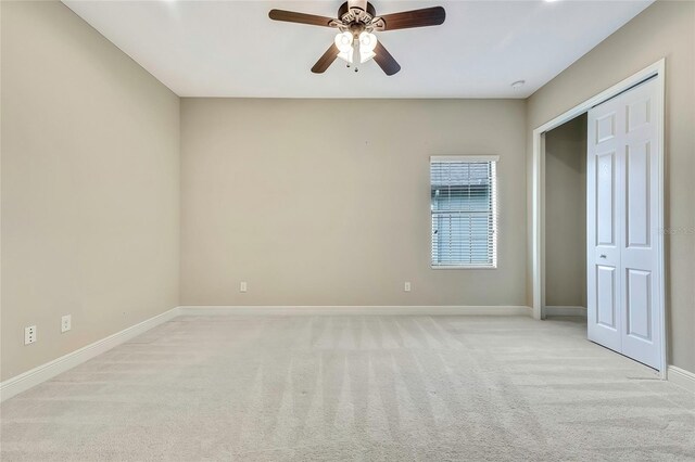 unfurnished bedroom with ceiling fan, a closet, and light carpet