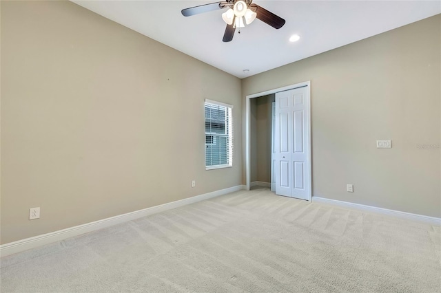 unfurnished bedroom featuring a closet, light colored carpet, and ceiling fan