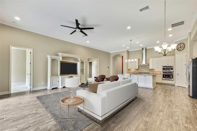 living room featuring light hardwood / wood-style flooring, ceiling fan with notable chandelier, and ornamental molding