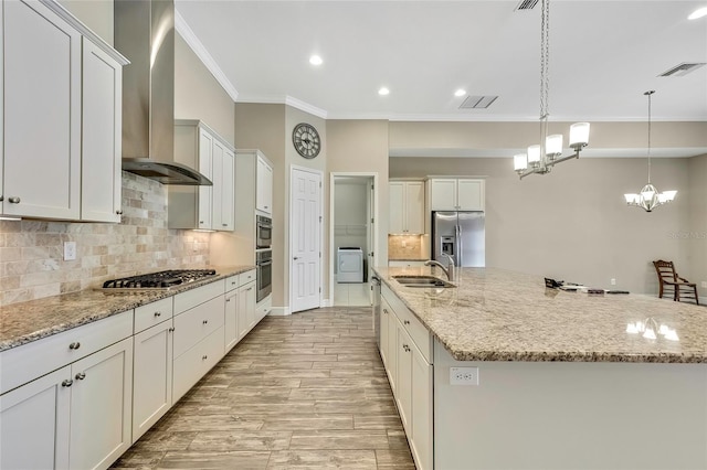 kitchen featuring appliances with stainless steel finishes, light wood-type flooring, wall chimney exhaust hood, white cabinetry, and a large island